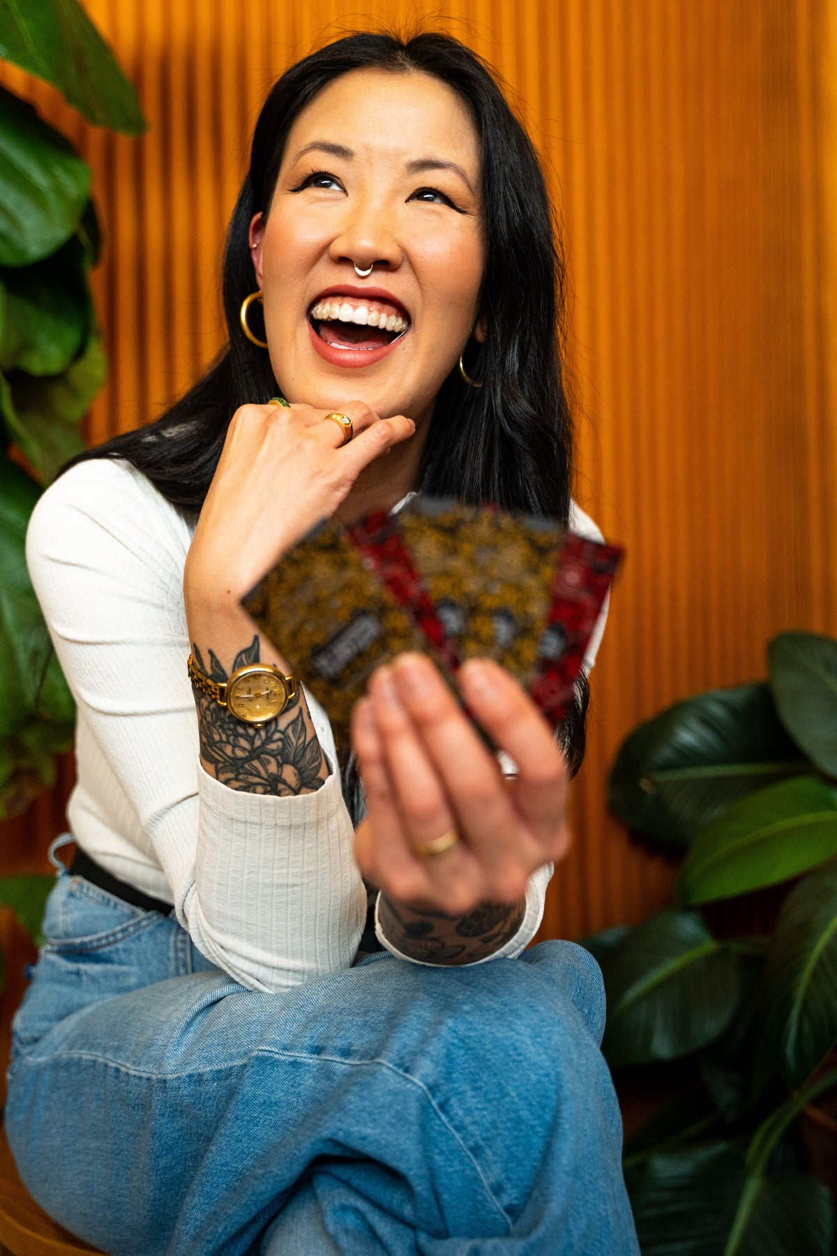 A smiling woman holding a hand of FLUSTER cards