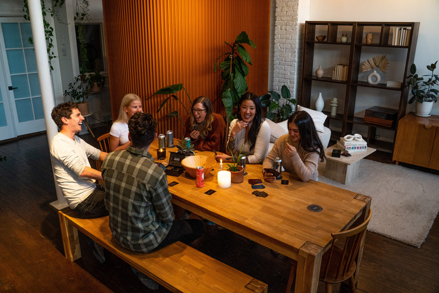 Six people at a table playing FLUSTER and laughing