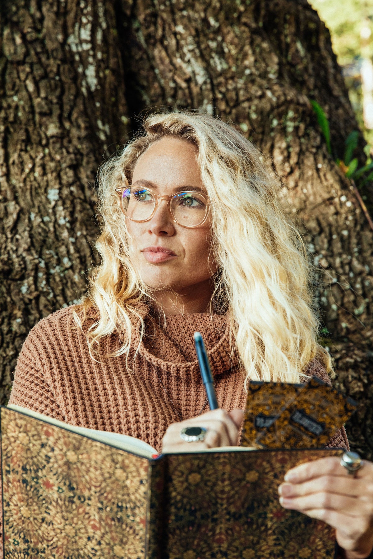 A woman sitting under a tree with a journal and FLUSTER cards