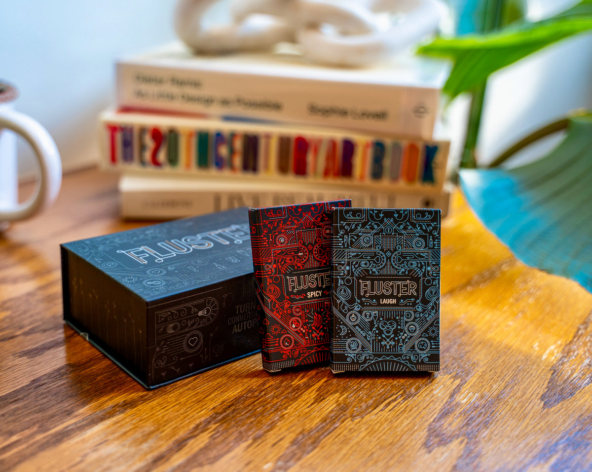 Fluster, the spicy pack, and the laugh pack on a table with books