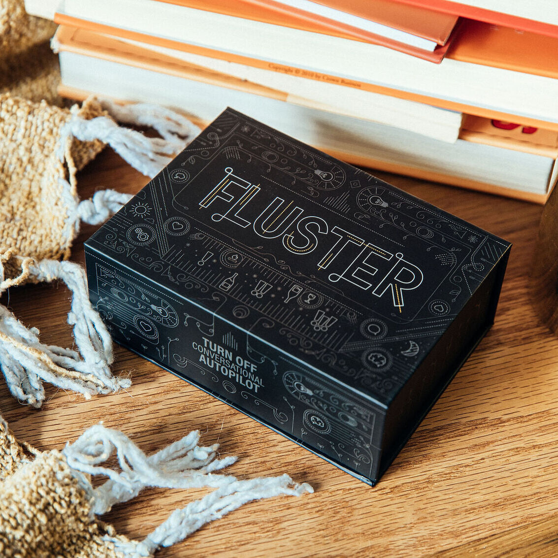 A FLUSTER card game box on a wood surface