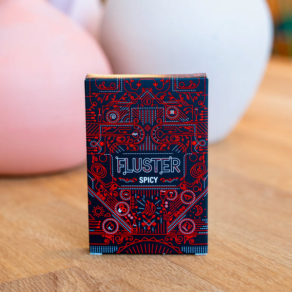 The FLUSTER Spicy Pack card game on a wooden surface