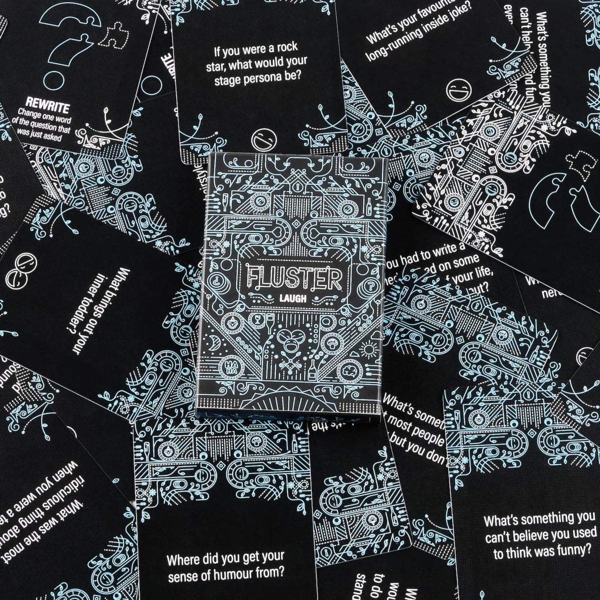 The blue Fluster Laugh Pack sits on top of scattered question cards, showcasing the intricate design and some questions and special cards.